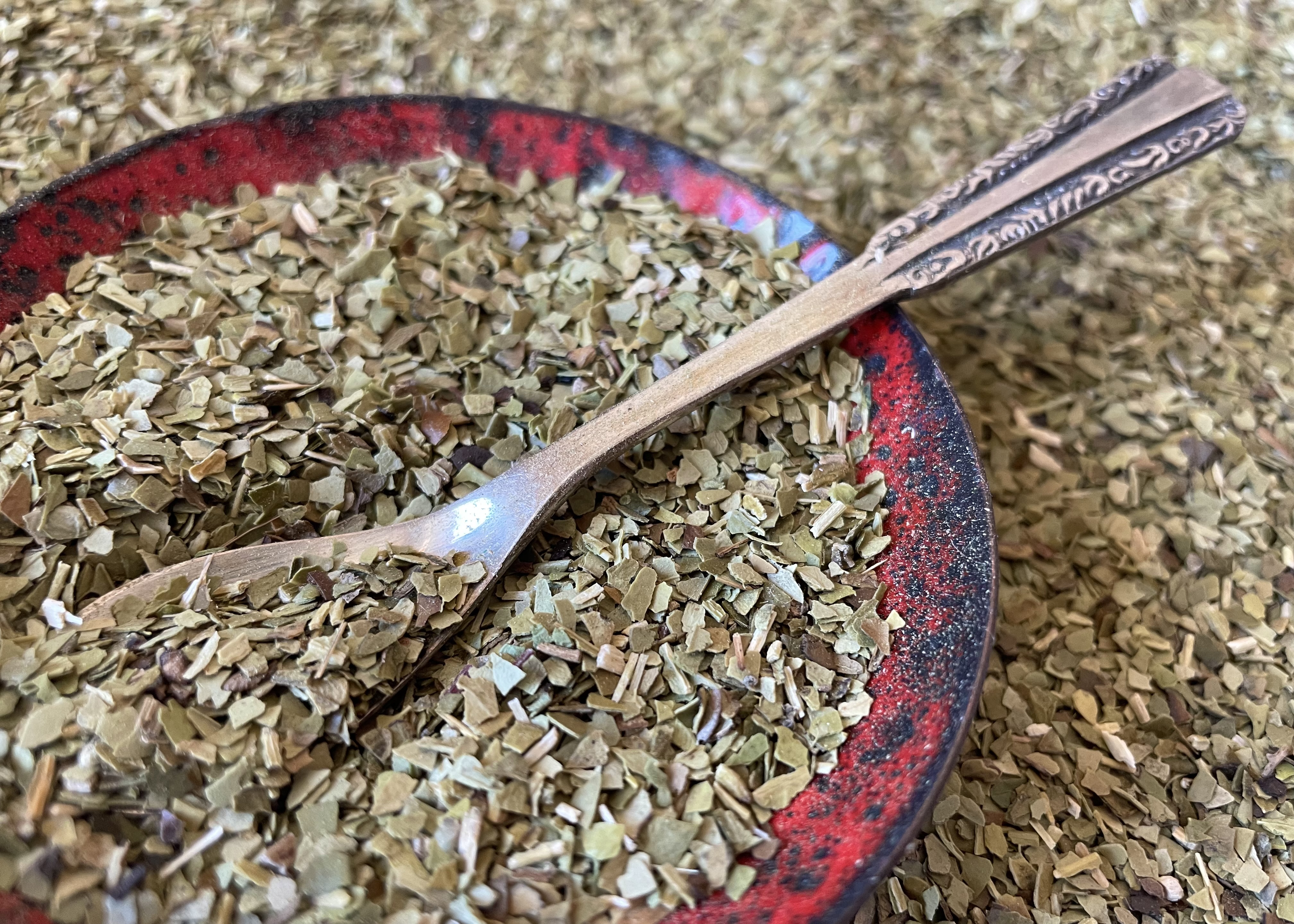 Loose Natural Green Mate Tea in a red bowl with silver spoon